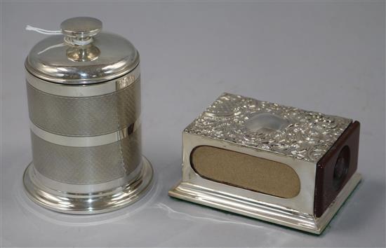A 1930s engine turned silver cylindrical cigarette dispenser, Birmingham, 1935 and a repousse silver matchbox holder on plinth base
